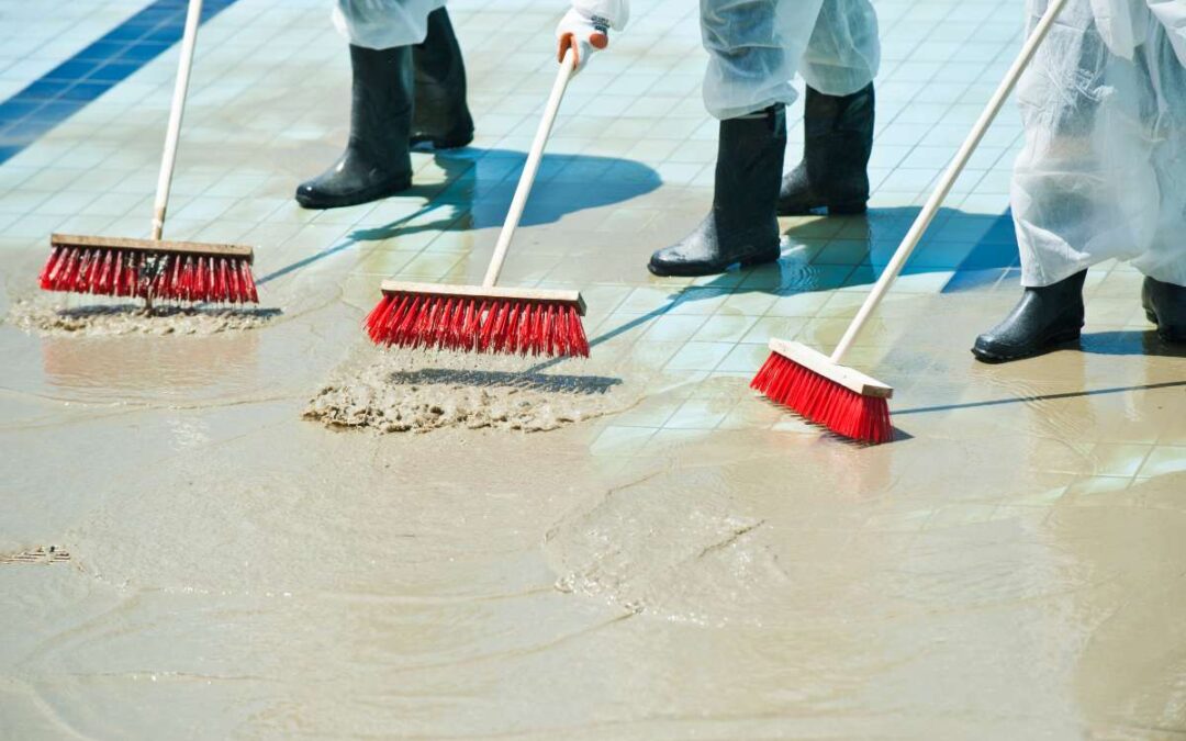 Des personnes utilisent des raclettes et des brosses pour nettoyer le sol après les inondations